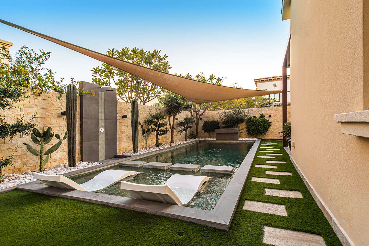 Garden design for villas featuring shaded plunge pool, cactus garden, and stone wall landscaping in Dubai.