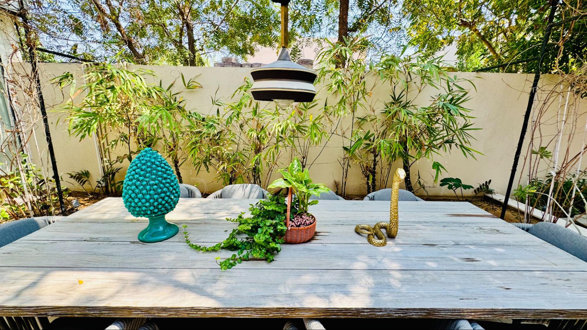 Outdoor dining garden design by Smart Renovation for Casa Gattopardo featuring bamboo screening, a rustic table and garden décor.
